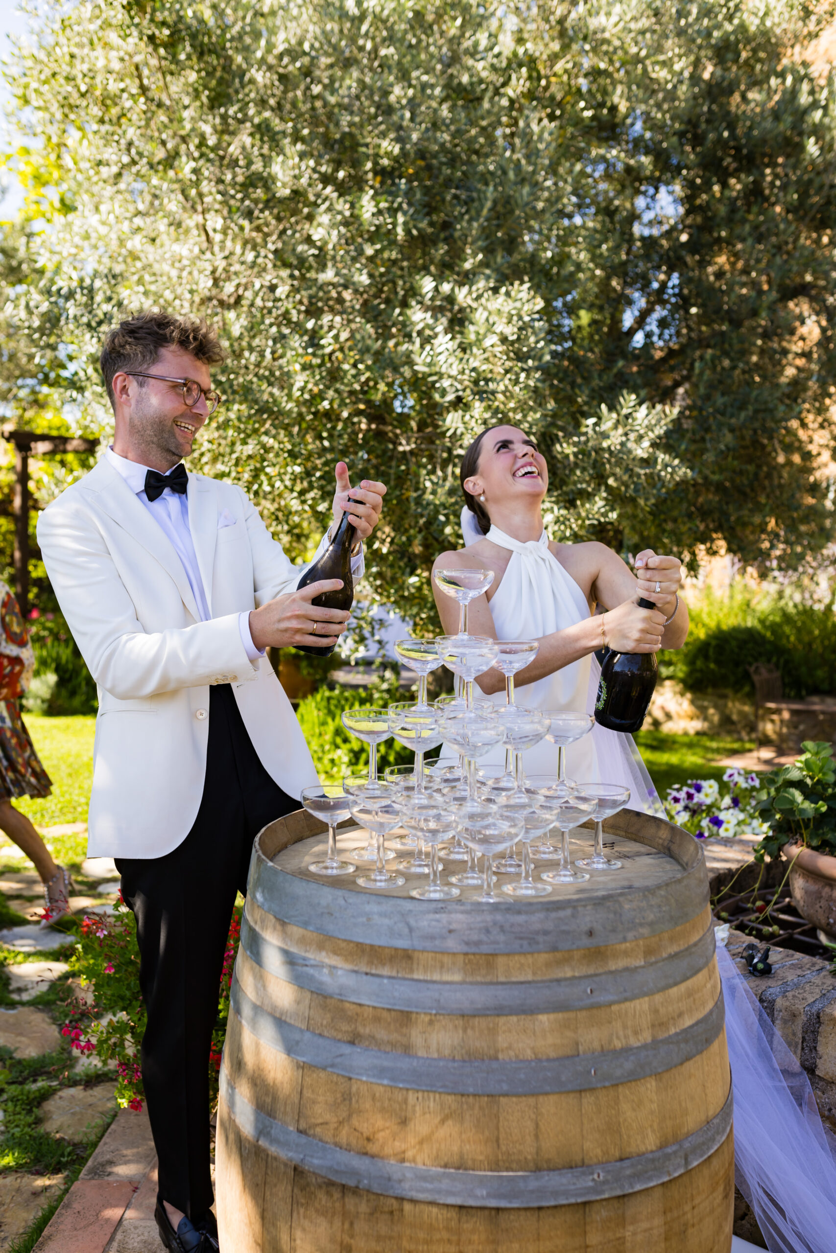 Green & Gold Weddings is Ilaria Krismer, a trusted Maremma-based Tuscany wedding planner couple popping champagne for champagne tower